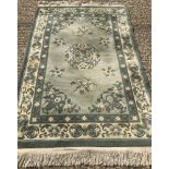 A cream and green floral design thick wool rug with fringed ends.