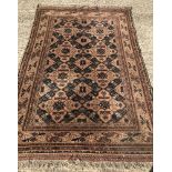 A wool rug with fringed ends. Brown ground with blue and brown geometric style pattern.