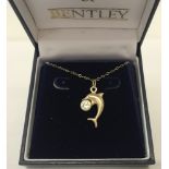 A 9ct gold dolphin holding a clear stone set ball on a fine belcher chain.