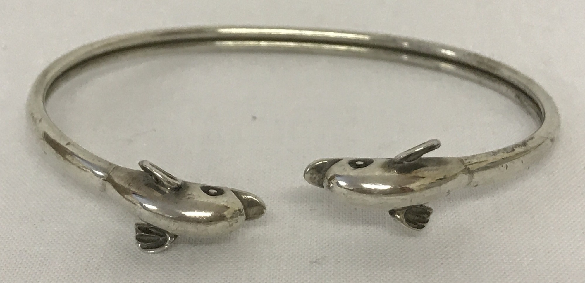 A 925 silver bangle with dolphin head detail.