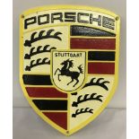 A painted cast iron Porsche wall hanging plaque, with fixing holes, in yellow, black and red.