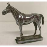 A vintage chrome figurine of a racehorse, possibly a car mascot.