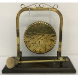 A vintage freestanding brass gong, mounted on wooden plinth, with beater.