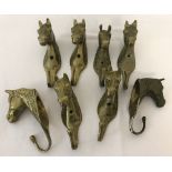 A collection of 8 vintage brass wall hanging hooks in the shape of horses heads.