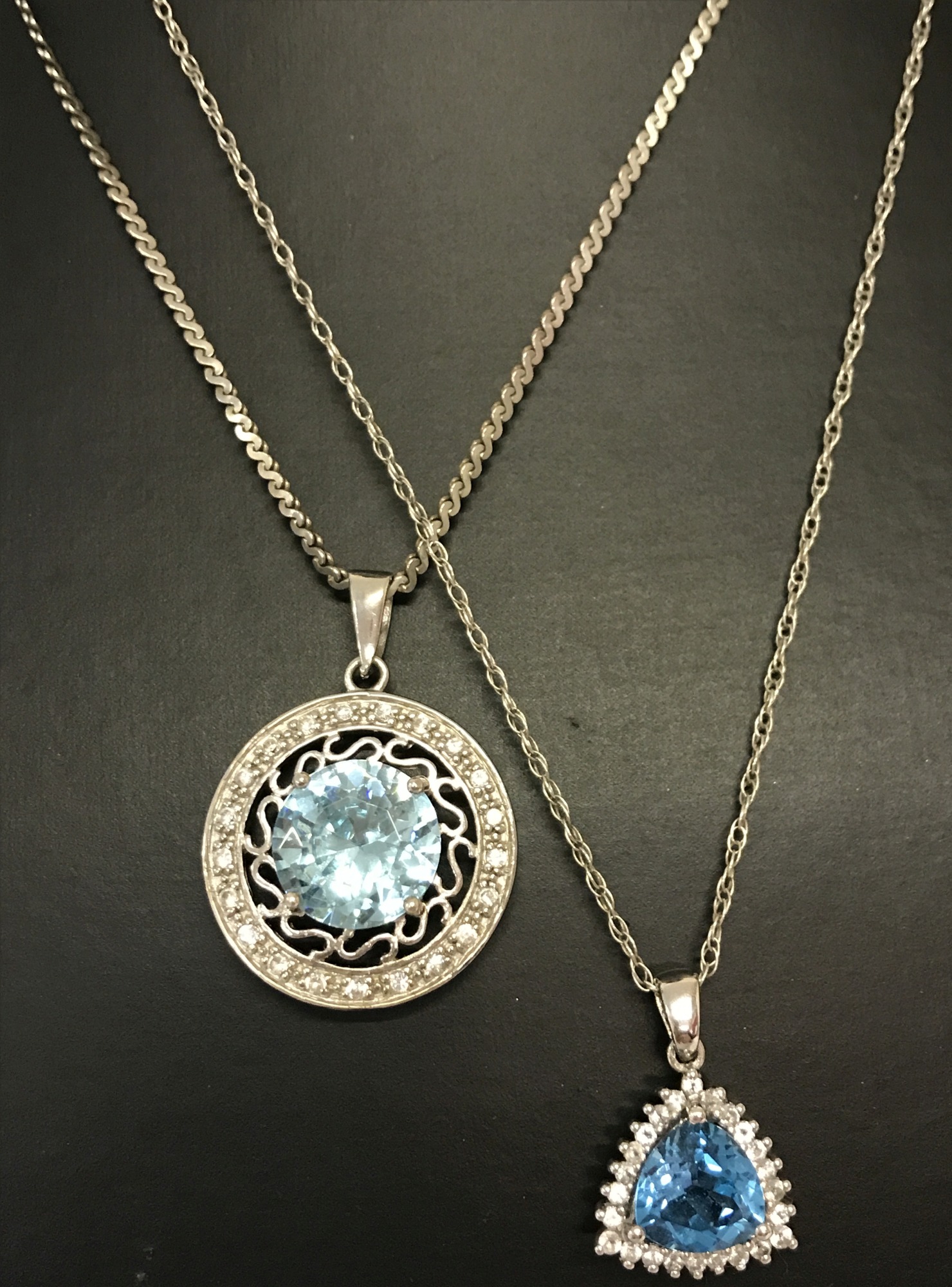 A decorative circular pendant set with a blue and clear cubic zirconia stones.