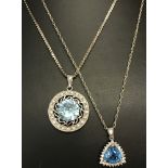 A decorative circular pendant set with a blue and clear cubic zirconia stones.