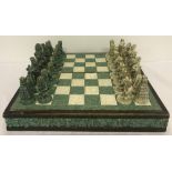 A vintage wooden and resin, highly carved chess board and pieces.