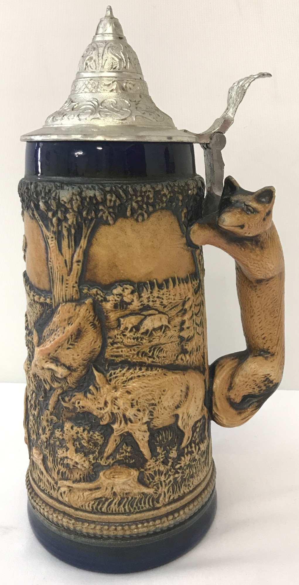 A large ceramic lidded stein with animal scene and fox shaped handle.