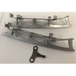 A pair of vintage metal ice skate shoe attachments with adjusting key.