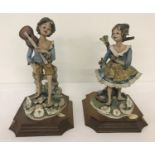 A pair of ceramic Capodimonte Bellinaso figurines of children, mounted onto wooden plinths.