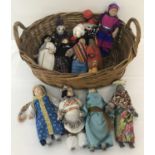 An oval wicker basket containing 11 porcelain-headed dolls.