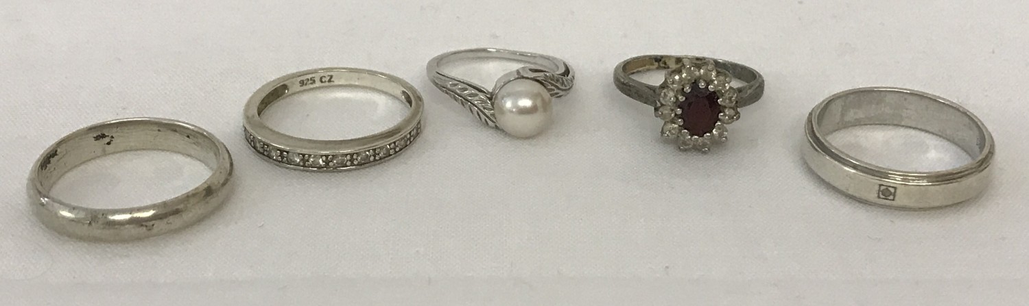 5 silver and white metal rings.