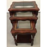 A nest of tables in dark wood with glass inset and brass stringing to top.