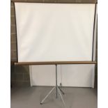 A vintage projector screen on tripod base.