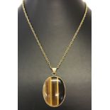 A large oval Tiger's Eye pendant set in a 9ct gold mount on a 24" inch 9ct gold chain.