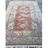 A large wool rug with fringed end with geometric and floral pattern.