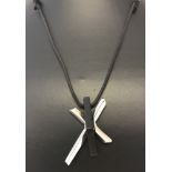 A contemporary design cross pendant on a black leather thong.