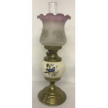A vintage brass and ceramic oil lamp with frosted glass shade.