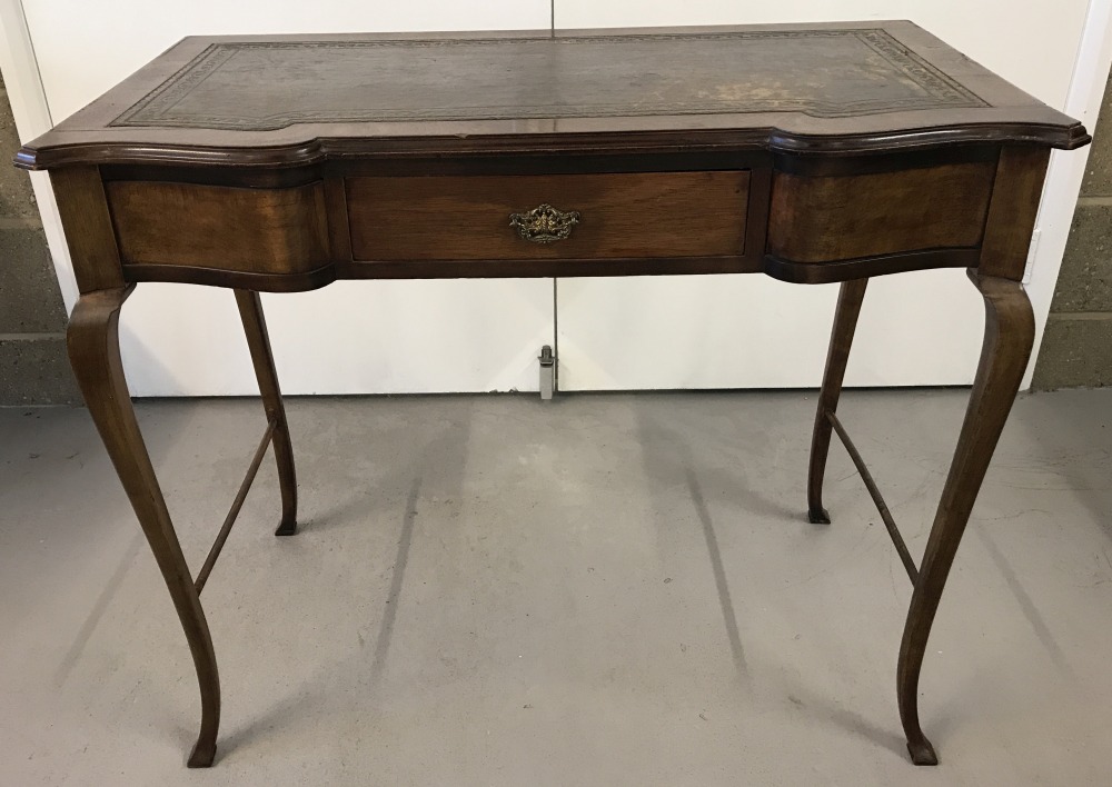 A vintage console table with serpentine front and tapered legs.