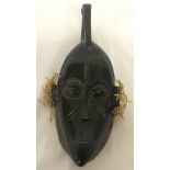 An African carved wooden tribal mask with plaited straw detail to sides.