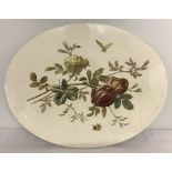 A large oval ceramic plaque with floral and insect decoration.