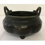 A large Chinese bronze censer with scalloped shaped bowl, 2 handles and raised on tripod feet.
