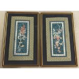 A pair of framed and glazed Oriental embroidered silk panels with floral design.