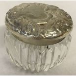 A small silver topped glass pot with Art Nouveau style detail to lid.