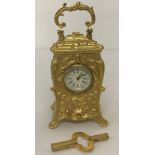 A miniature decorative gilt bronze carriage clock complete with key.