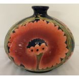 A large ceramic vase, in the style of Moorcroft, of bulbous form with red/orange flower detail.