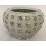 A white glaze Chinese porcelain pot with calligraphy detail.