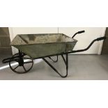 A vintage galvanised metal wheelbarrow with cast iron wheel and rubber grips to handles.