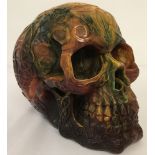 A large carved multi coloured resin skull figurine decorated with Pagan style symbols.