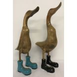 2 wooden figurines of ducks wearing boots.