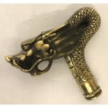 A brass walking cane handle in the shape of a Chinese dragon head.