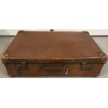 A large vintage suitcase in tan leather-look material.