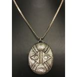 A large antique silver locket with floral engraving to front, on a serpentine style chain.