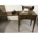 A vintage dark wood cased table treadle singer sewing machine together foot pedal & accessories.
