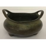 A small Chinese bronze 2 handled censer raised on tripod feet.