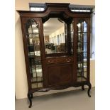 A Victorian mirror backed glass fronted display cabinet with central cupboard and drawer.