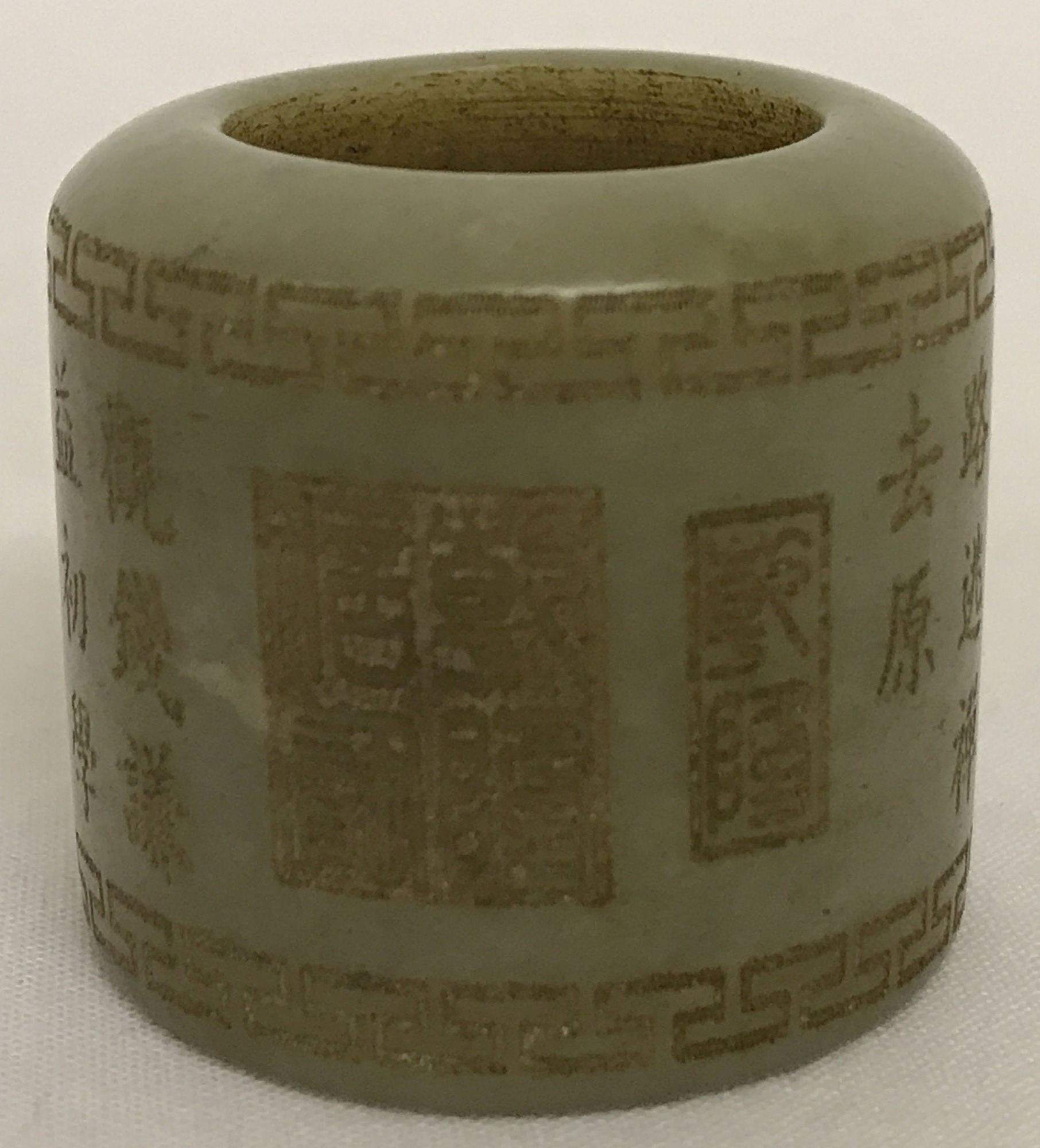 A jade archers ring with carved Greek Key design to top and bottom rim and Chinese characters around