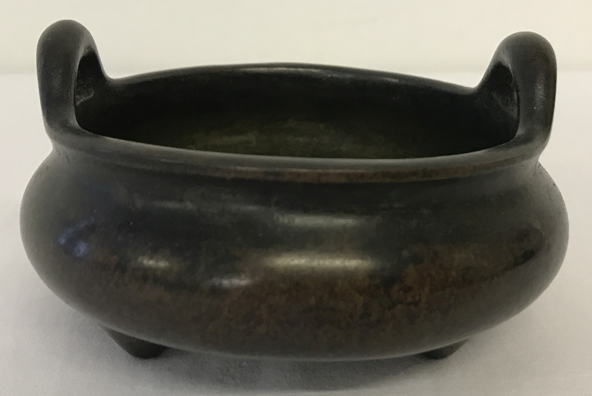 A heavy Chinese bronze 2 handled censer raised on tripod feet.