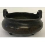 A heavy Chinese bronze 2 handled censer raised on tripod feet.