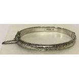 A vintage silver half engraved bangle complete with safety chain.