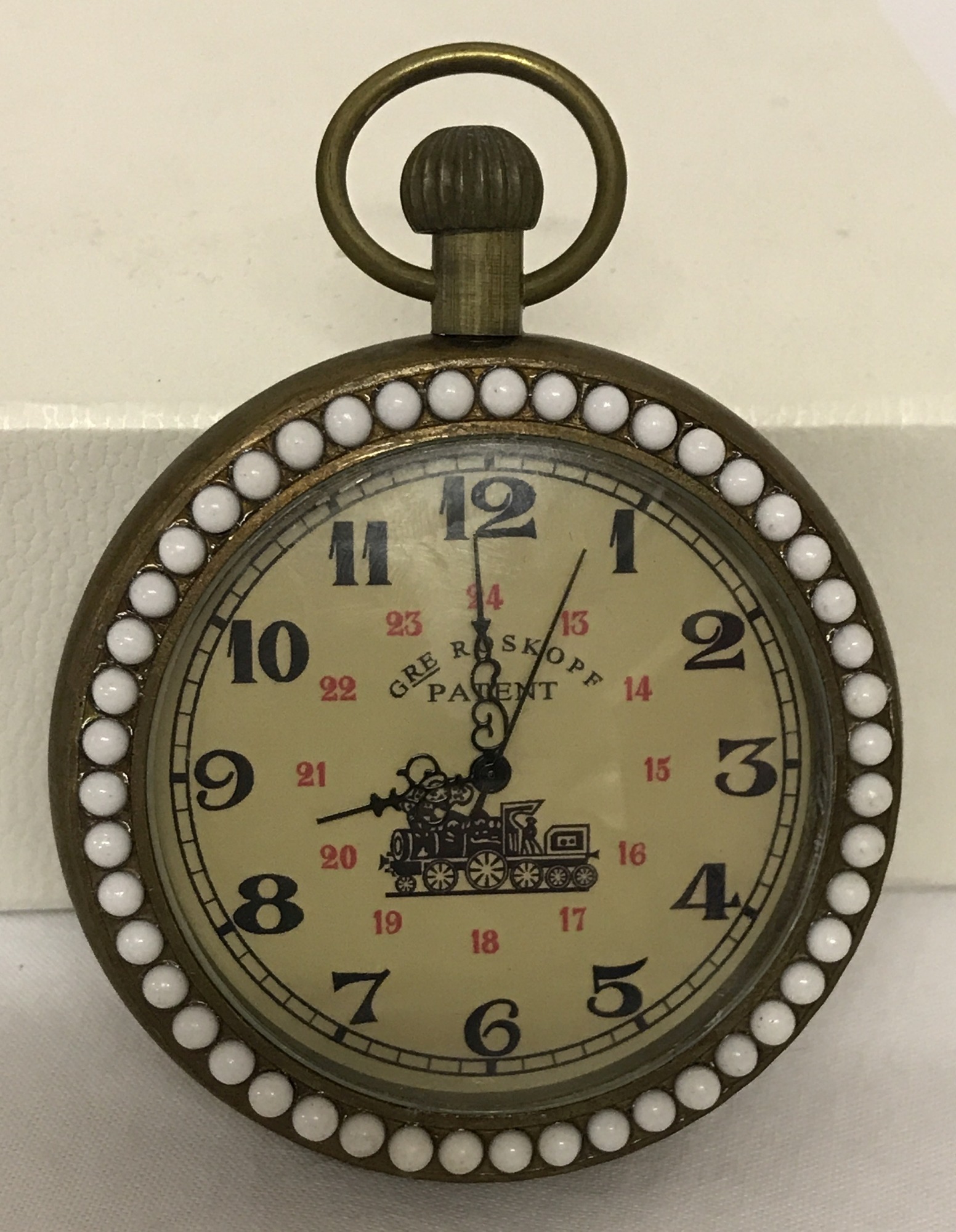 A brass cased pocket watch with beaded detail to surround front and back.