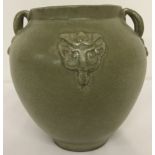 A 2 handled green glaze ceramic vase with details in relief front and back.
