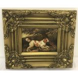 A gilt framed oil on board of a tan and white dog under a tree.