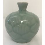A small Chinese ceramic vase of bulbous form. Duck egg blue glaze with lotus flower petal detail.