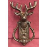 A cast iron stag head door knocker with scroll detail to fixing plate.