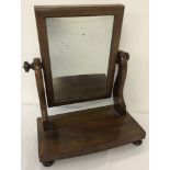 A small Edwardian dressing table swing mirror, on bun feet and with turned finials.